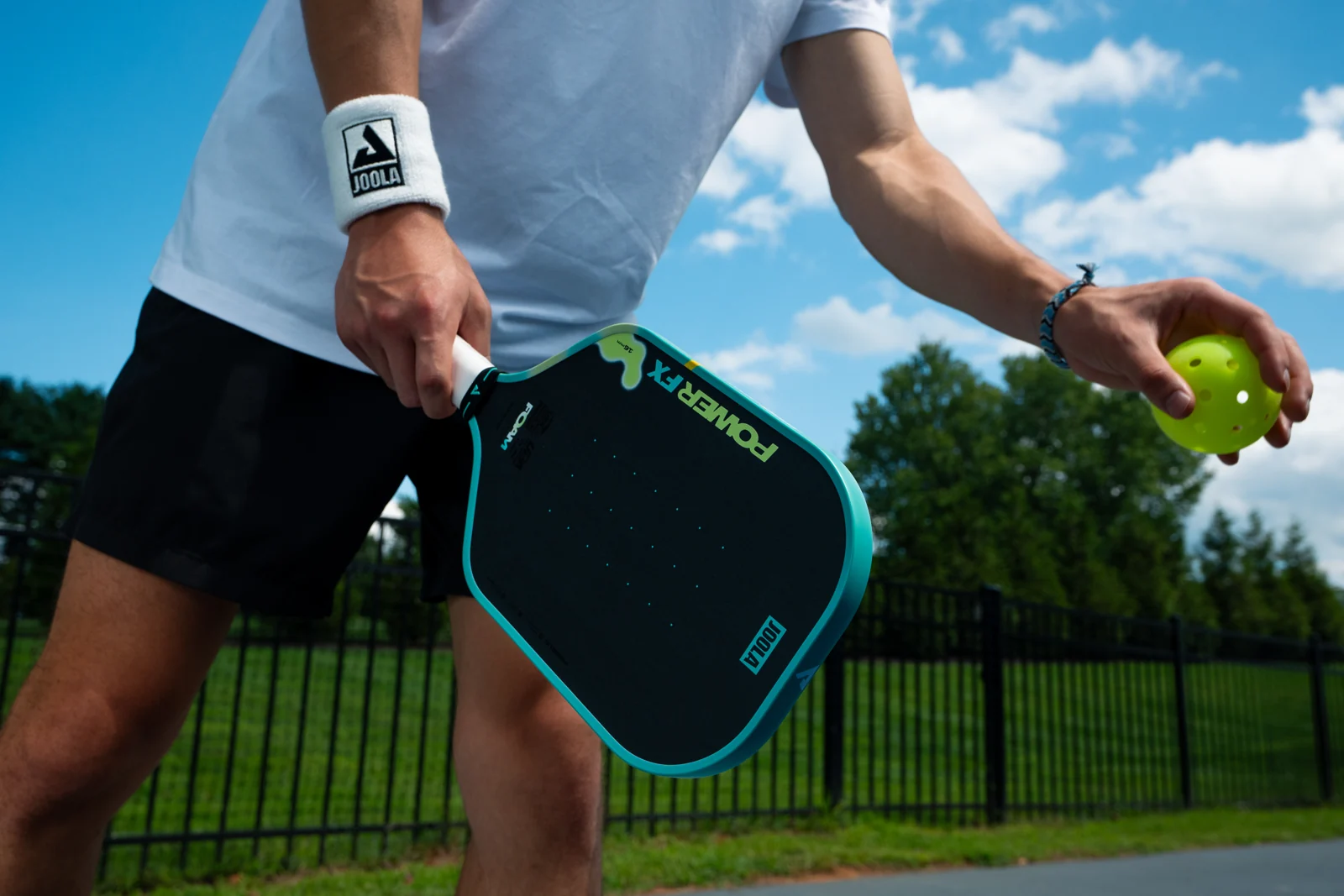 Joola Power FX Daydream và bóng pickleball trong tay người chơi